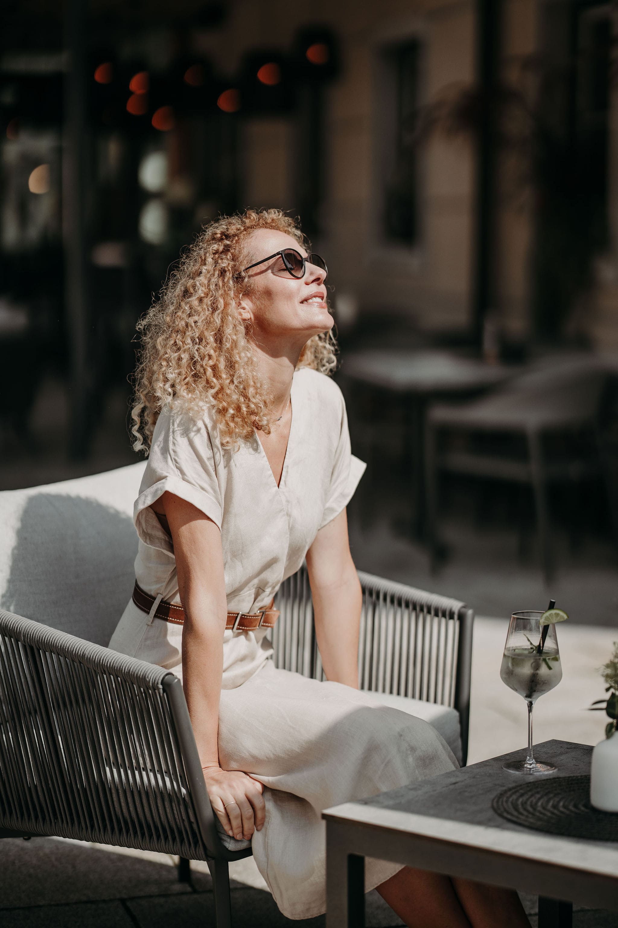 Frau sitzt entspannt im Freien mit Sonnenbrille
