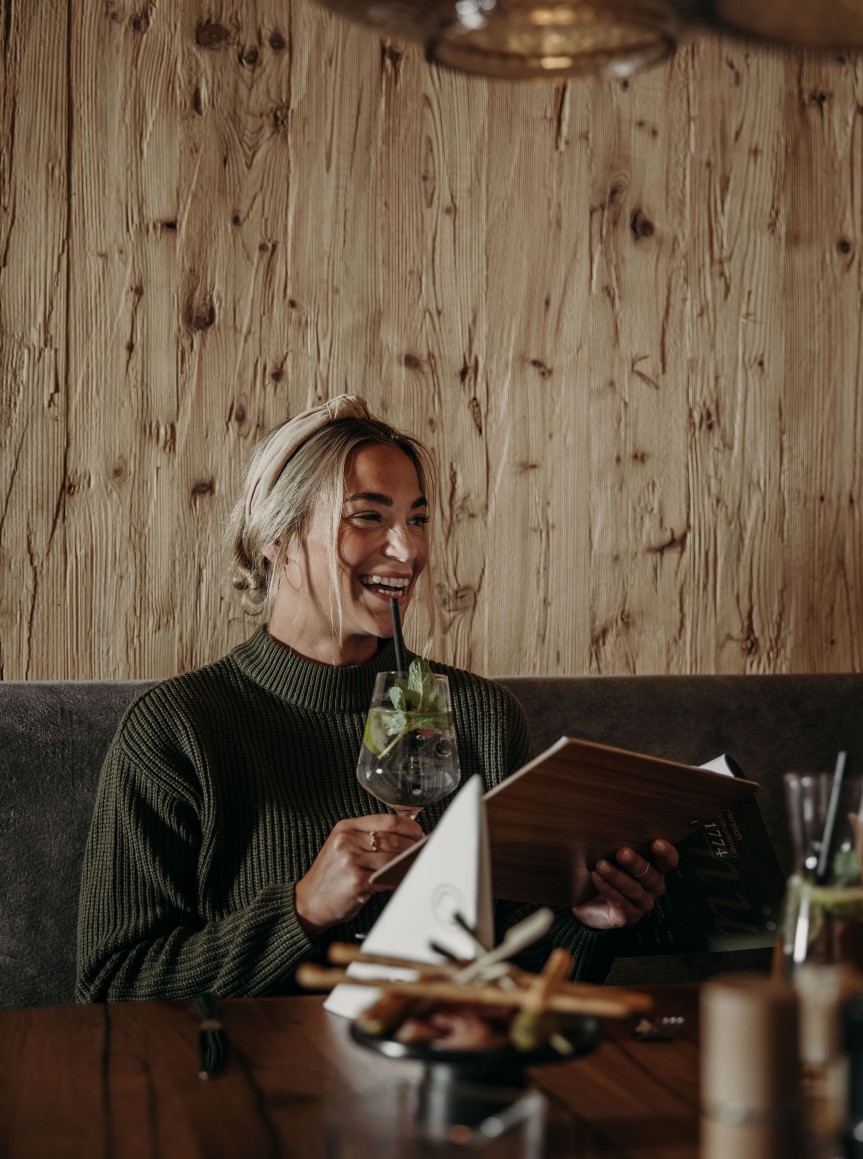 Frau genie&szlig;t ihren Drink beim Abendessen